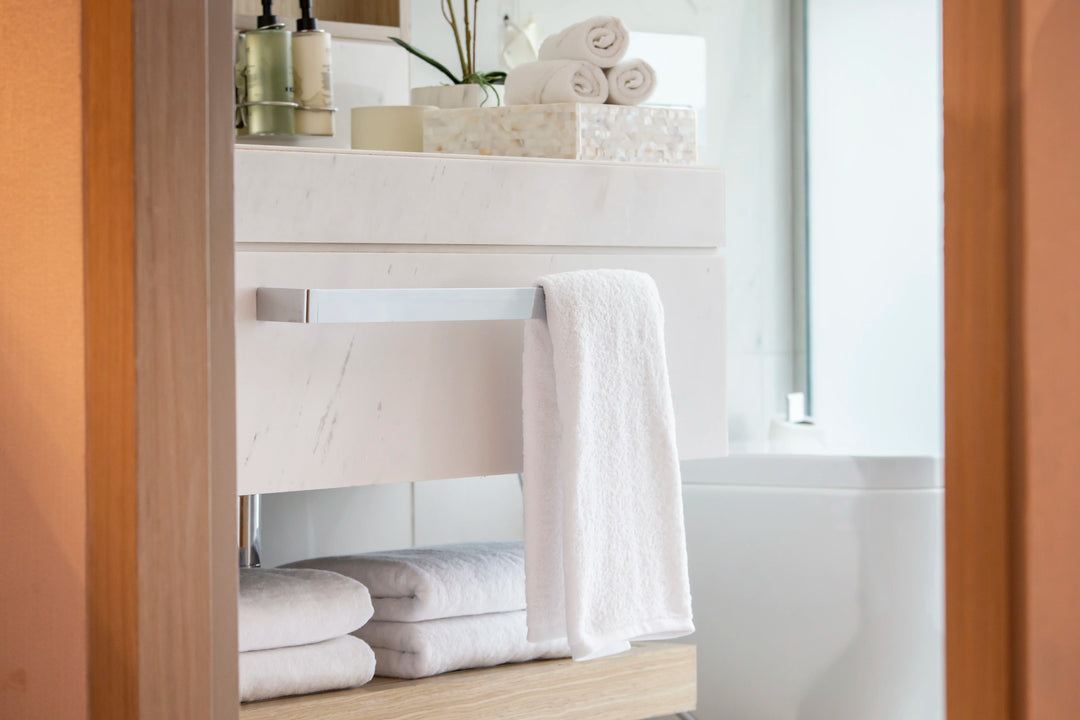 Retreat white cotton towels in a marble bathroom, seen through an open doorway