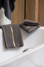Grey Chateau Turkish cotton hand towels on the edge of a bathtub 