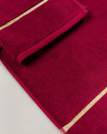 Maroon Chateau Turkish cotton bath mat, close-up of the gold dobby border and soft terry pile 