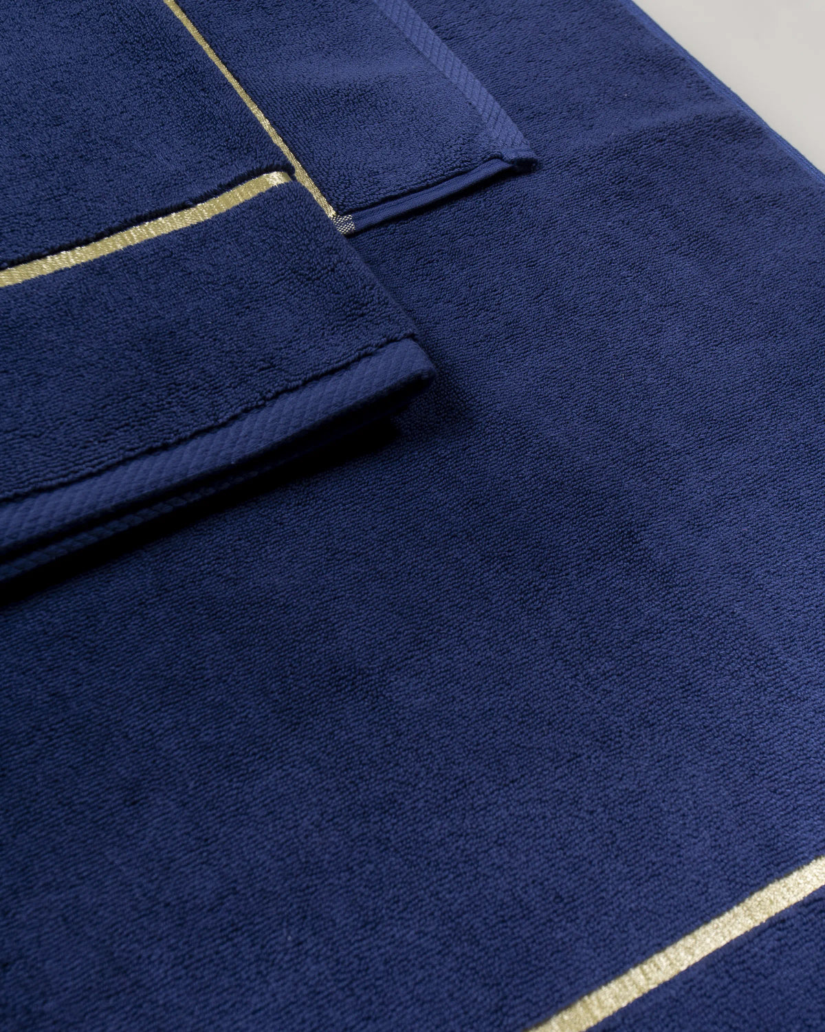 Navy Blue Chateau Turkish cotton bath mat, close-up of the gold dobby border and soft terry pile 