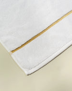 White Chateau Turkish cotton bath mat, close-up of the gold dobby border and soft terry pile 