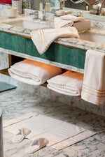 White Chateau Turkish cotton bath mat, on a marble bathroom floor with white slippers 