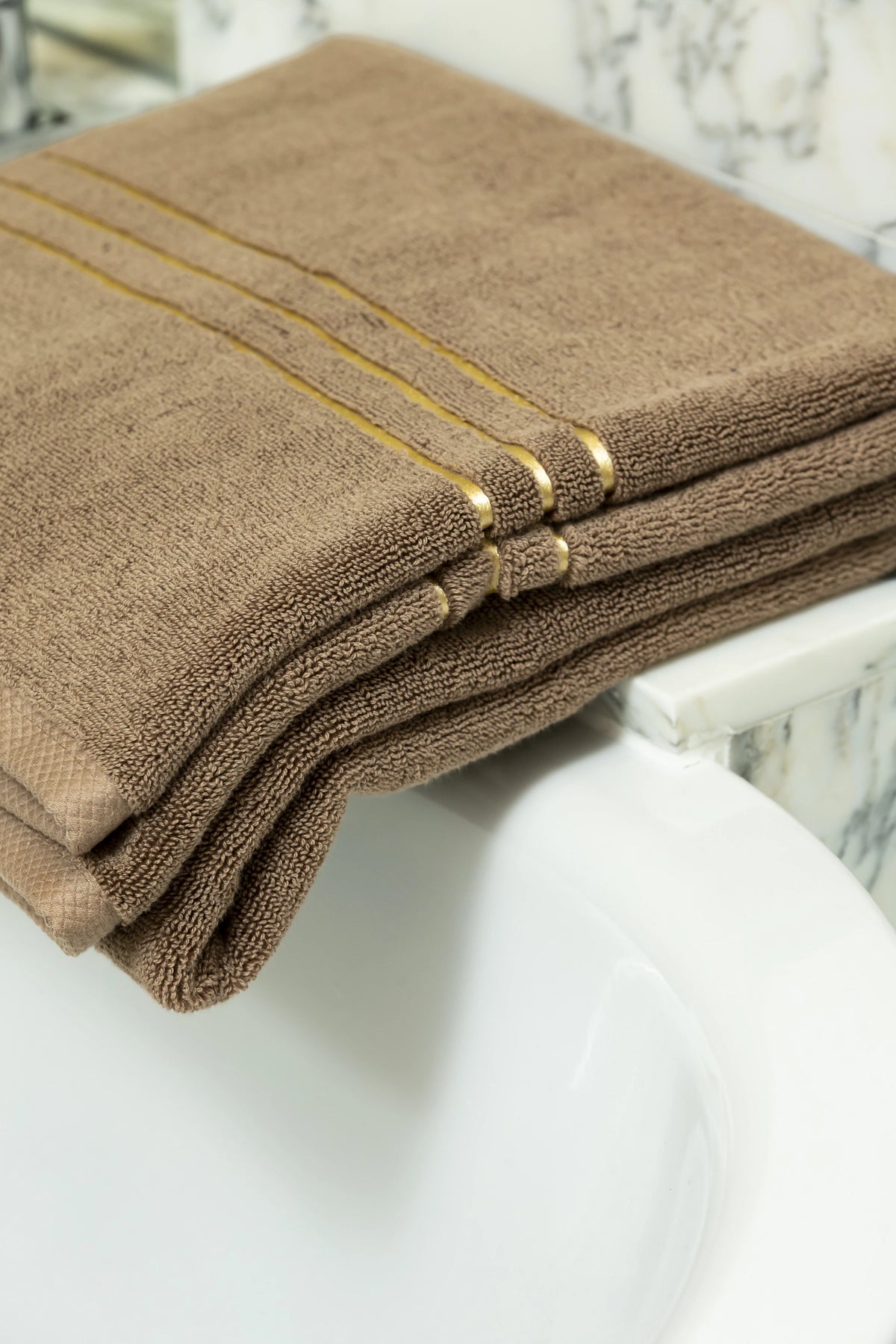 Brown Chateau Turkish cotton bath sheet, draped over the edge of a bathtub 