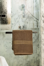 Brown Chateau Turkish cotton bath sheet, on a chrome bar in a glass shower 