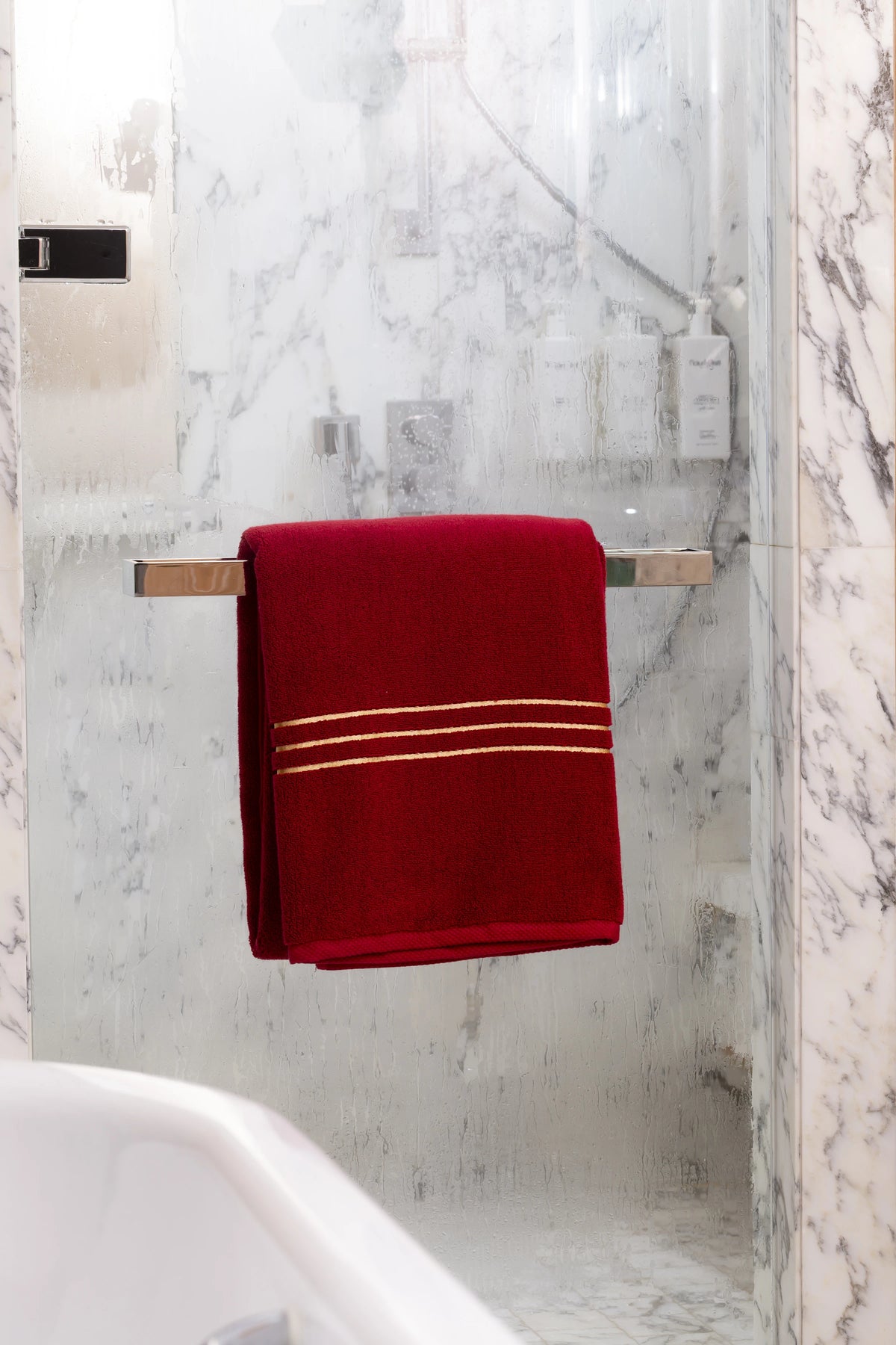 Maroon Chateau Turkish cotton bath sheet, on a chrome bar in a glass shower 