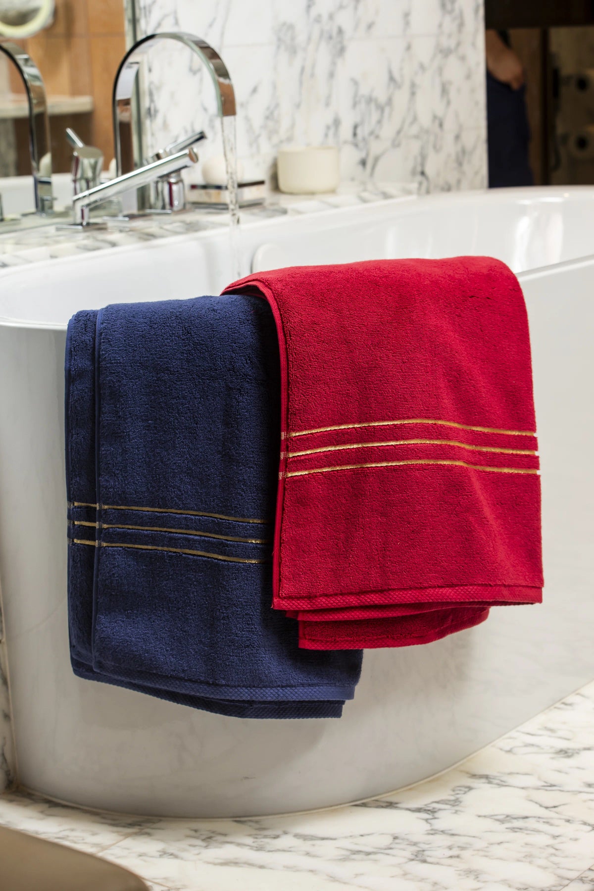 Navy blue and maroon Chateau Turkish cotton bath sheets draped over a freestanding bathtub 