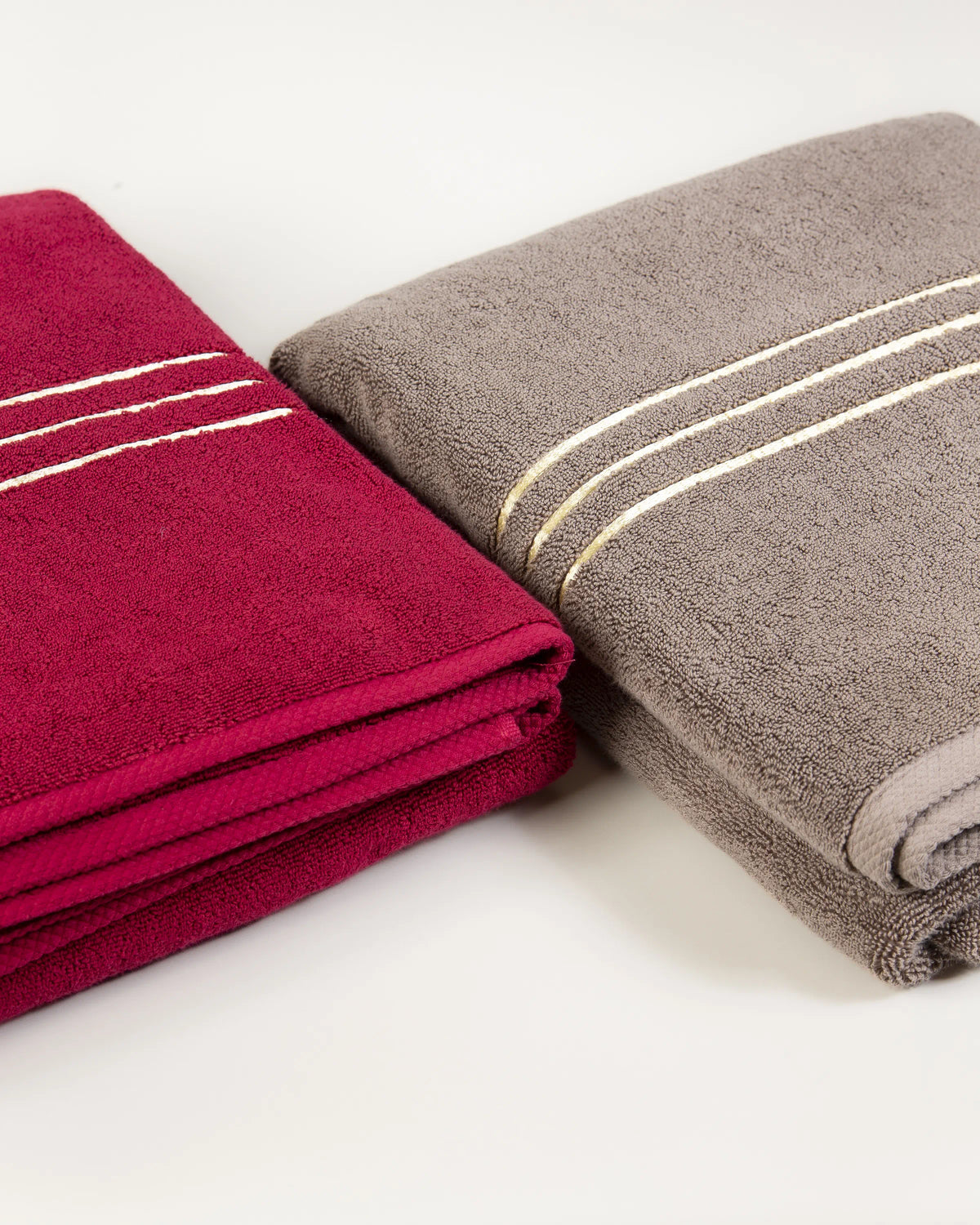 Maroon and brown Chateau Turkish cotton bath sheets folded side by side, gold border lines on each 