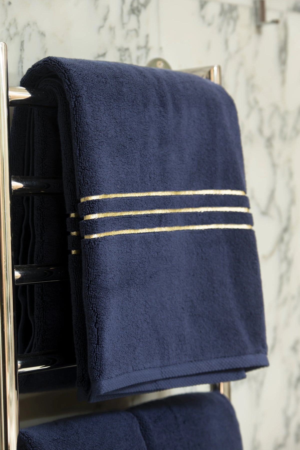 Navy Blue Chateau Turkish cotton bath sheet, on a heated towel rail in a marble bathroom 