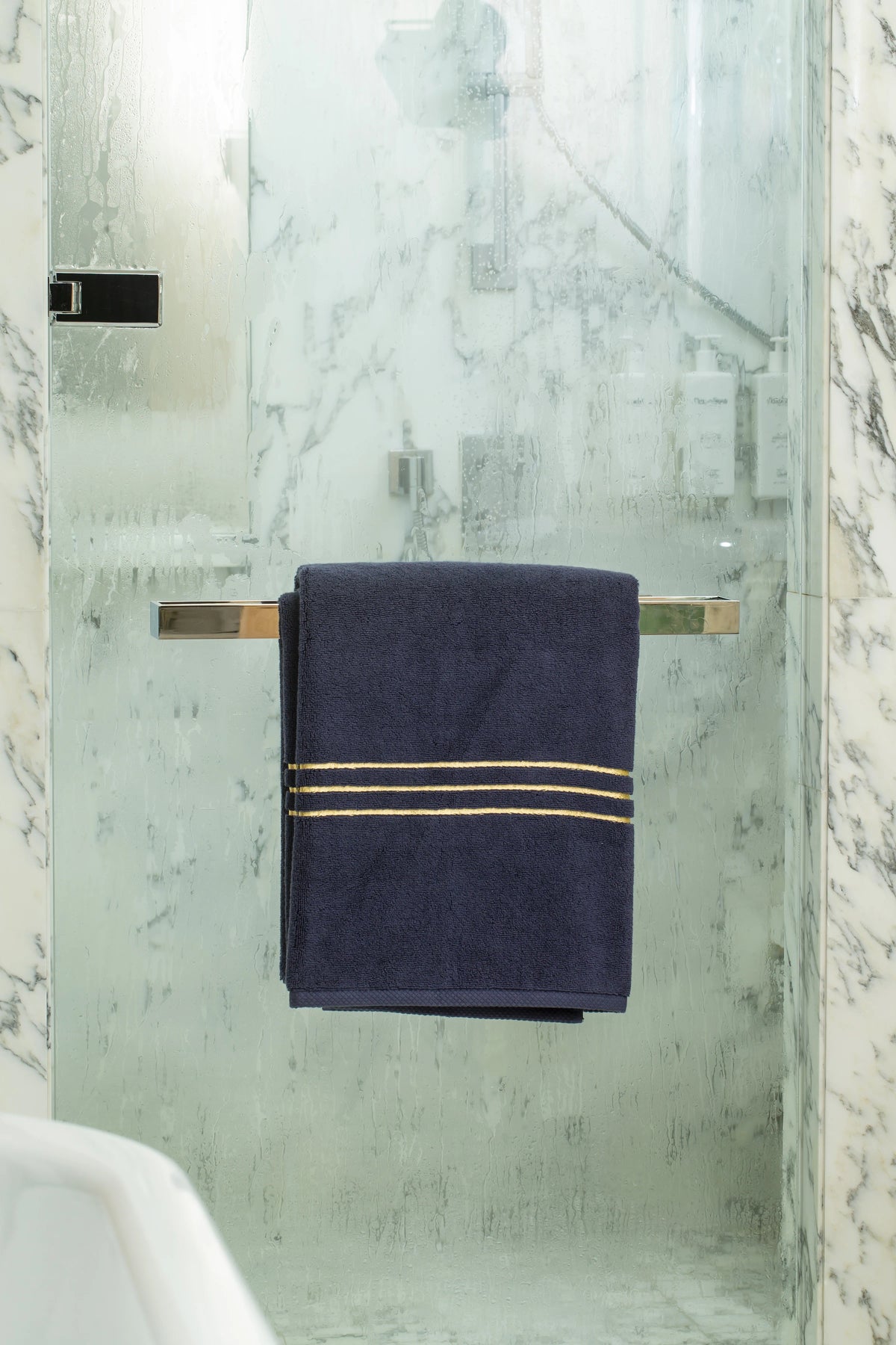 Navy Blue Chateau Turkish cotton bath sheet, on a chrome bar in a glass shower 