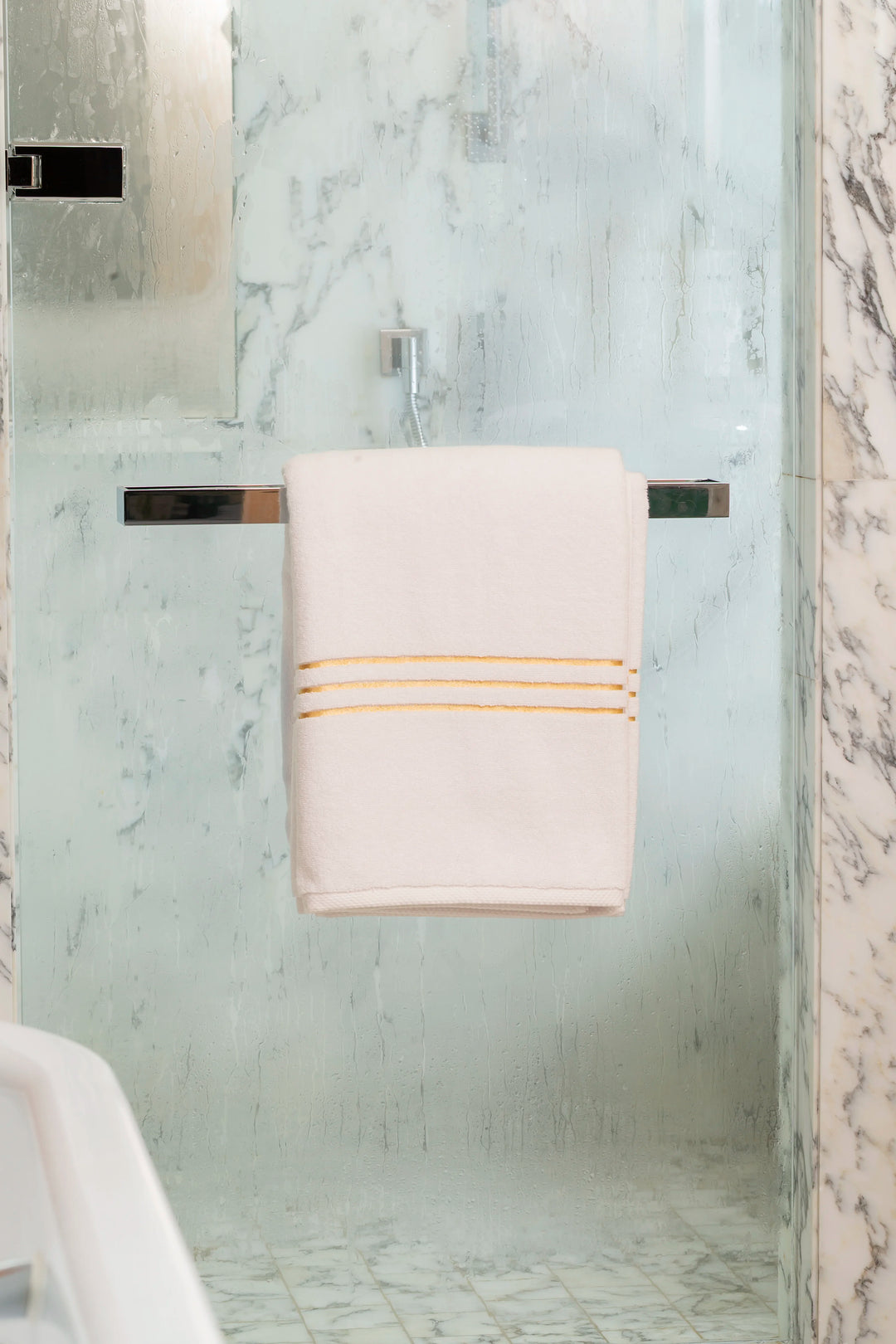 White Chateau Turkish cotton bath sheet, on a chrome bar in a glass shower 