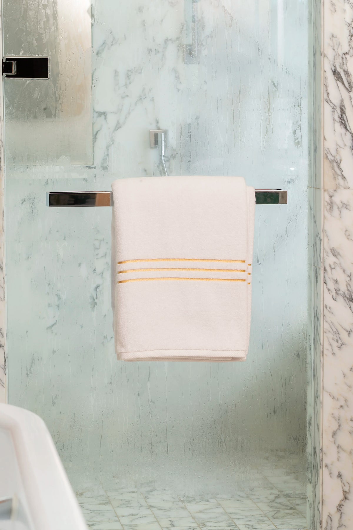 White Chateau Turkish cotton bath sheet, on a chrome bar in a glass shower 