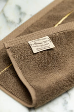 Etiqueta tejida Maison 1952 Colección Chateau en una toalla de baño de algodón turco, color marrón 