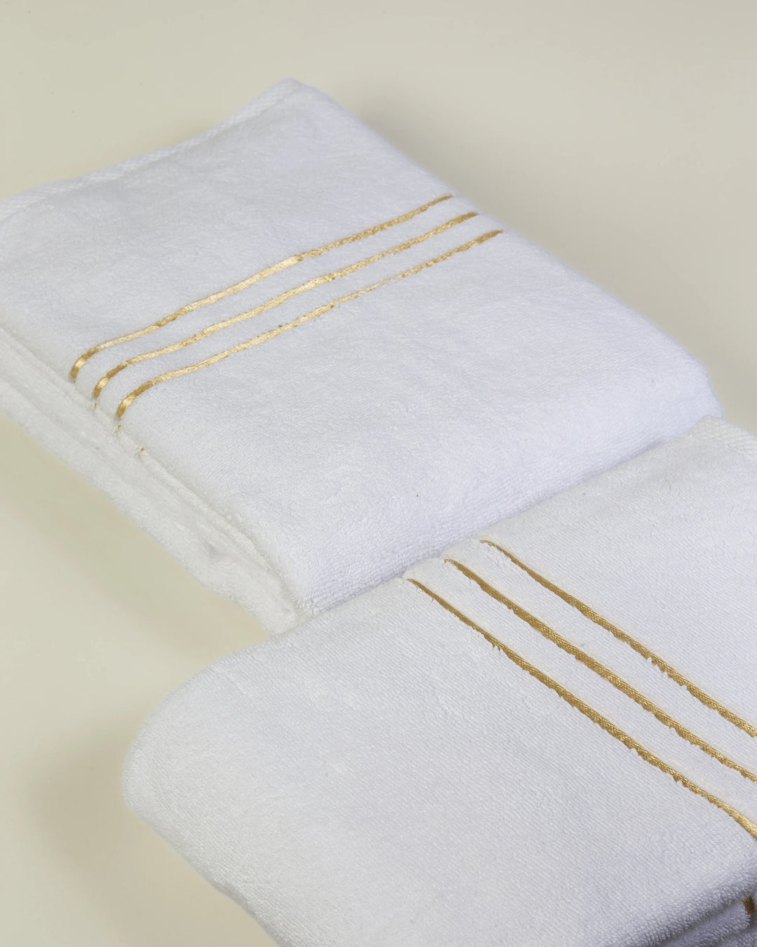 White Chateau Turkish cotton bath towel, two folded, close-up of the gold dobby borders 