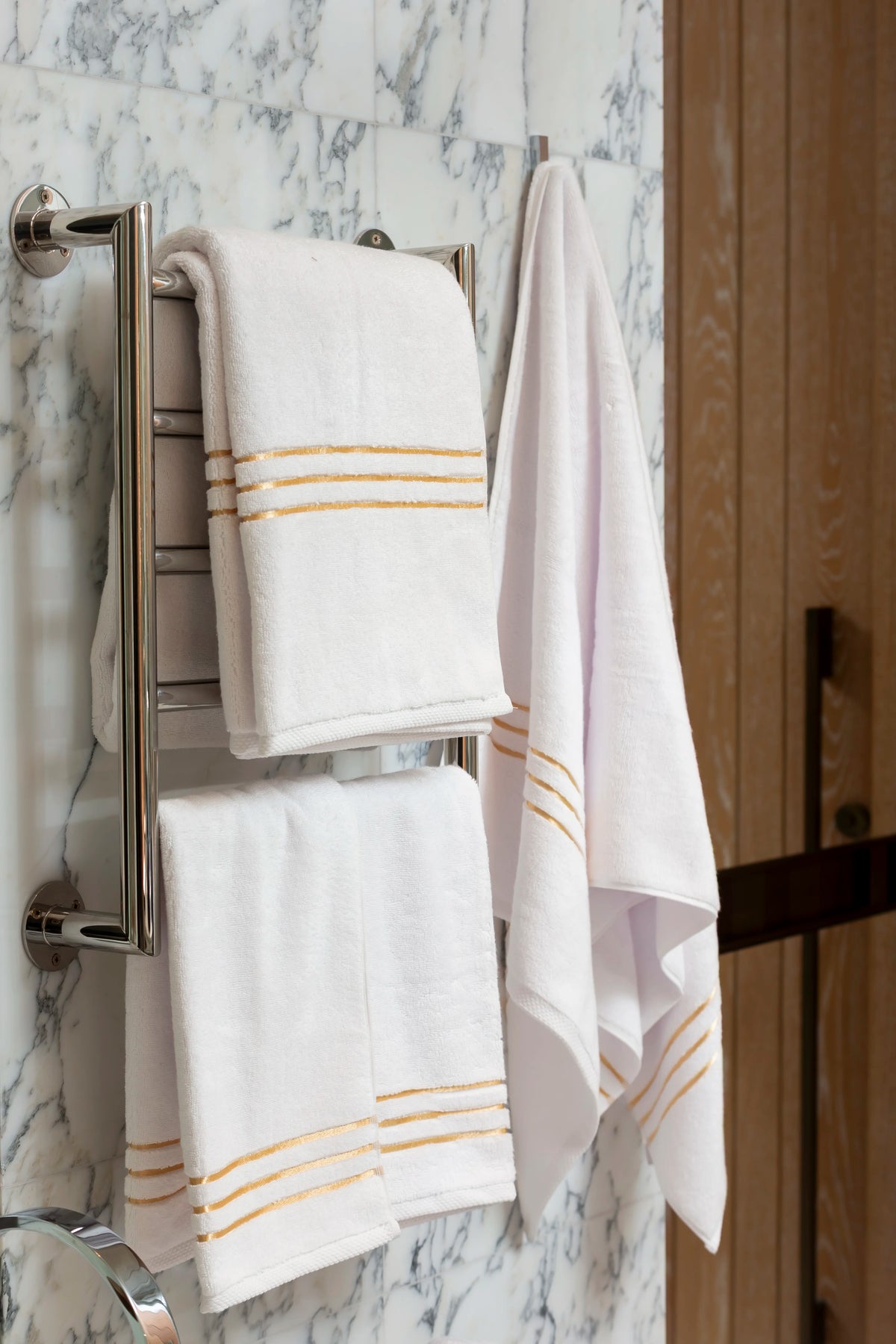 Toalla de baño Chateau de algodón turco, color blanco, en un toallero eléctrico en un baño de mármol 