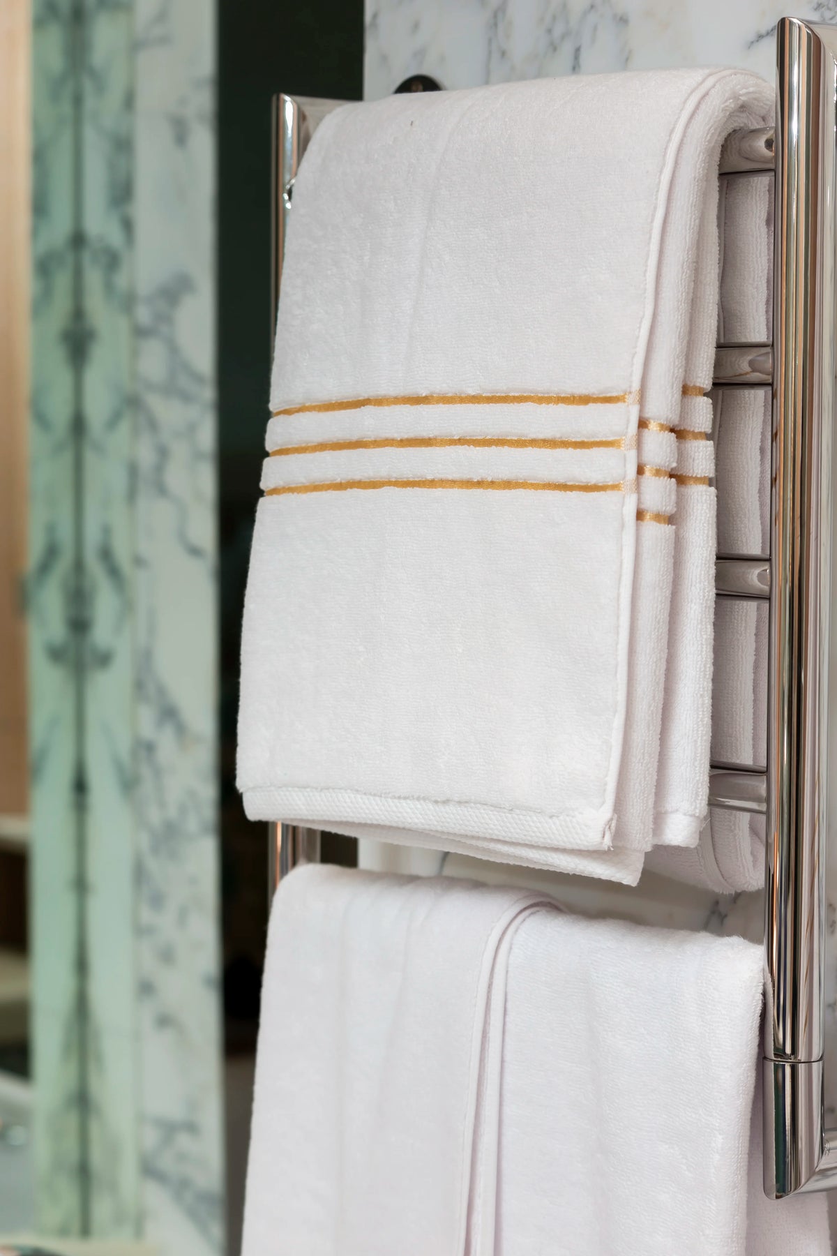 Toalla de baño Chateau de algodón turco, color blanco, en un toallero eléctrico en un baño de mármol 