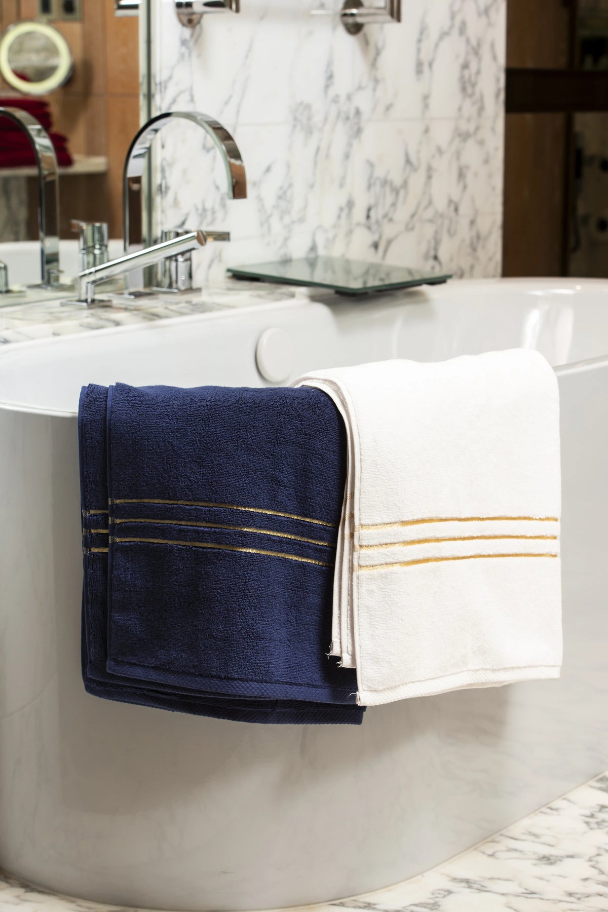 Chateau Duo set colour pairing: navy blue and white towels draped over a freestanding bathtub