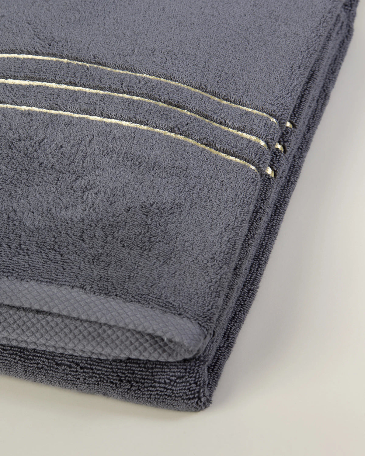 Set Chateau Essentials, colore grigio – primo piano delle righe dorate sul telo da bagno piegato 