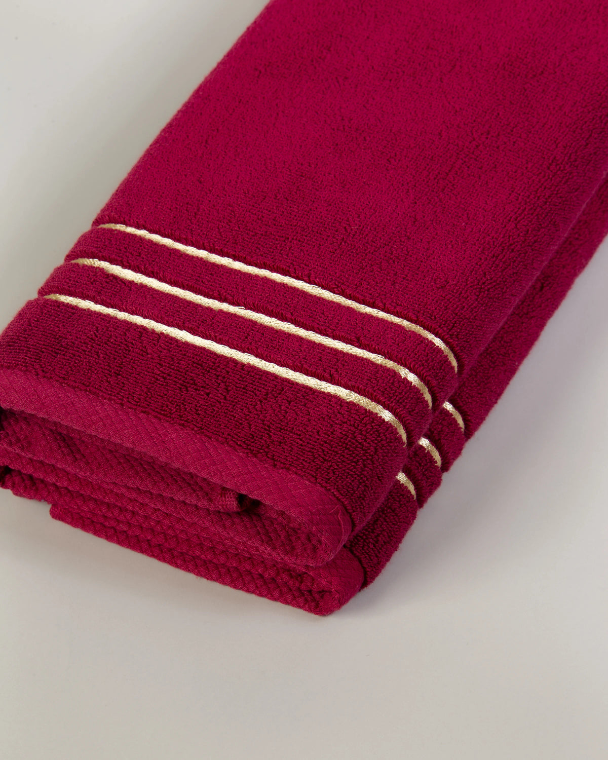 Set Chateau Essentials, colore bordeaux – primo piano delle tre righe dorate sul telo da bagno piegato 
