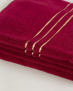 Set Chateau Essentials, colore bordeaux – primo piano del bordo dorato sugli asciugamani impilati 
