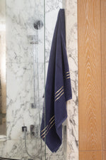 Set Chateau Essentials, colore blu navy – telo da bagno appeso in una doccia di marmo e vetro 