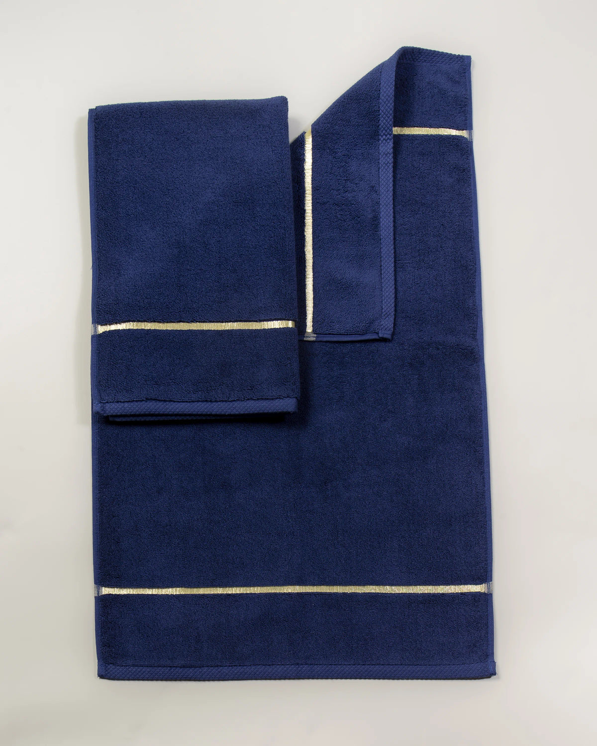 Set Chateau Essentials, colore blu navy – tappeto da bagno steso in piano con due asciugamani sopra 