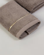 Brown Chateau Turkish cotton face towel, close-up of the gold dobby border and soft terry pile 