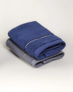 Navy blue and grey Chateau Turkish cotton face towels folded together, each with a single gold border line 
