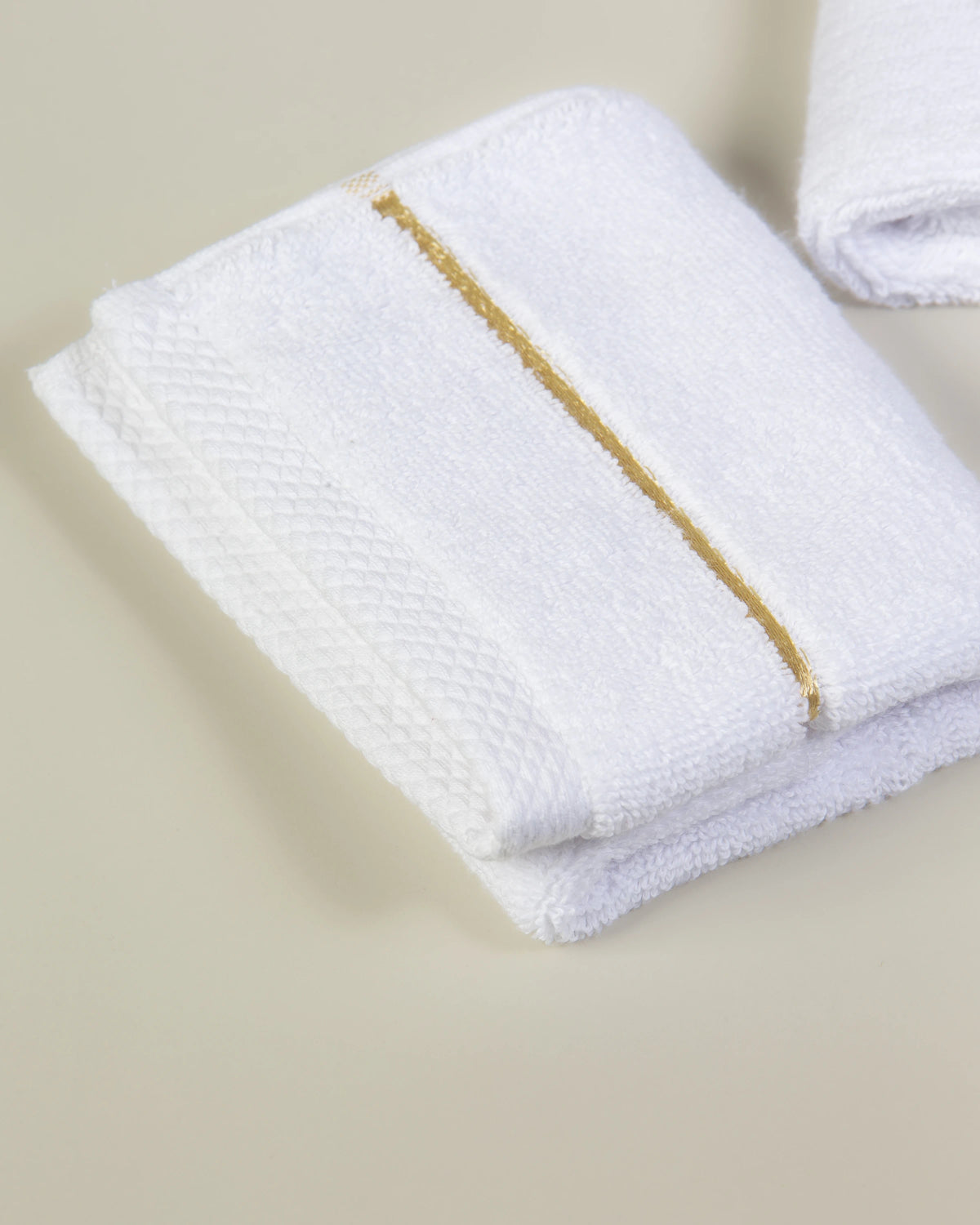White Chateau Turkish cotton face towel, close-up of the gold dobby border and soft terry pile 