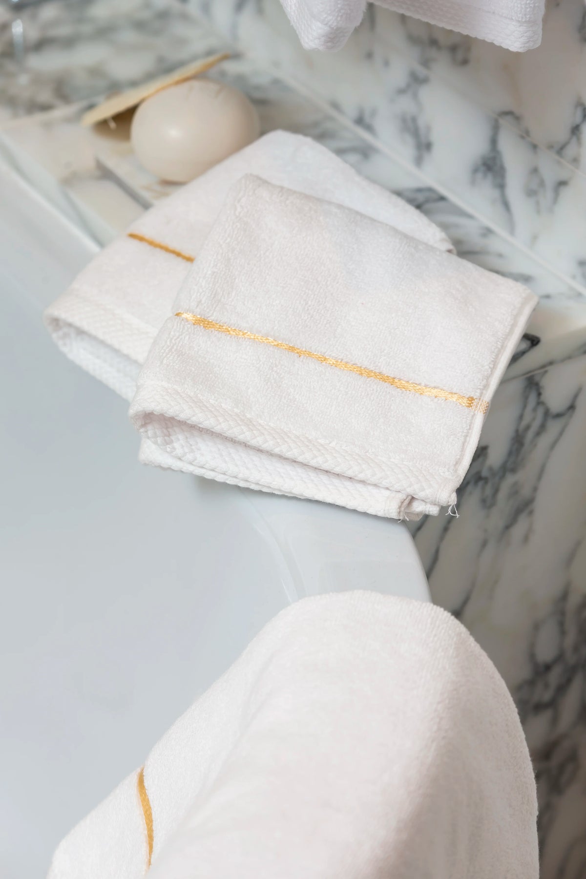 White Chateau Turkish cotton face towel, draped over the edge of a bathtub 