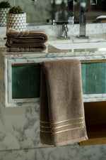 Brown Chateau Turkish cotton hand towel, hanging from a marble vanity 
