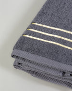 Grey Chateau Turkish cotton hand towel, close-up of the gold dobby border and soft terry pile 