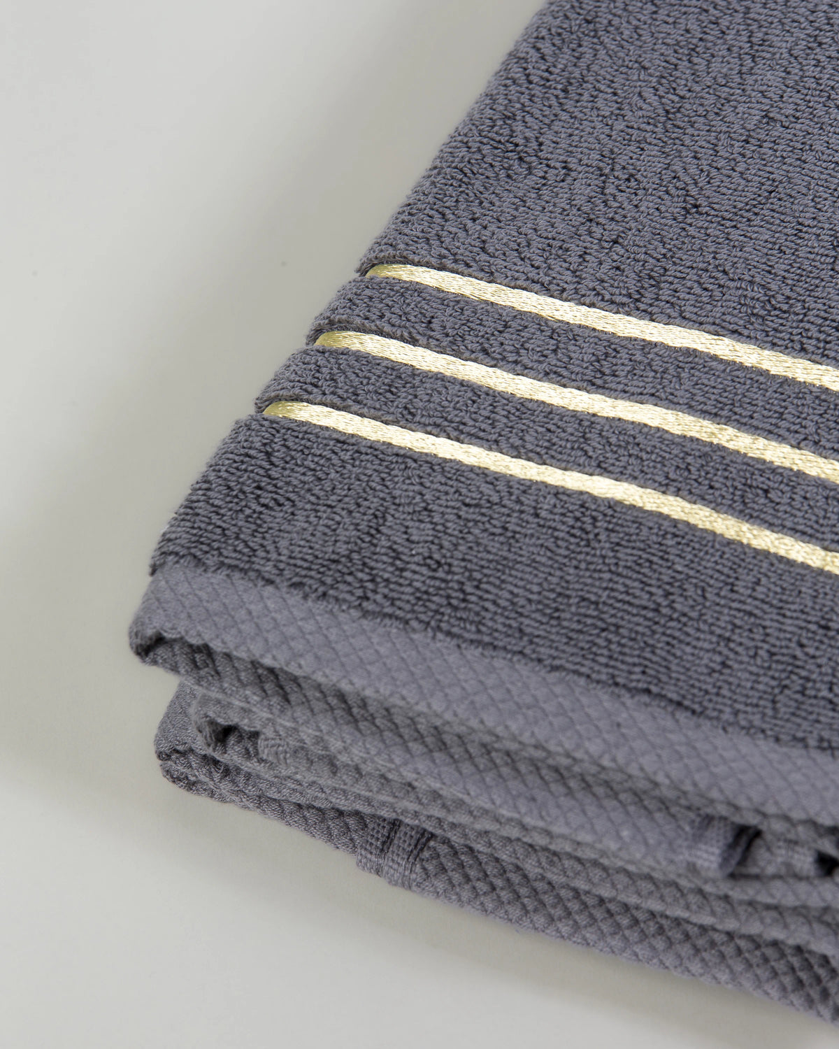 Grey Chateau Turkish cotton hand towel, close-up of the gold dobby border and soft terry pile 