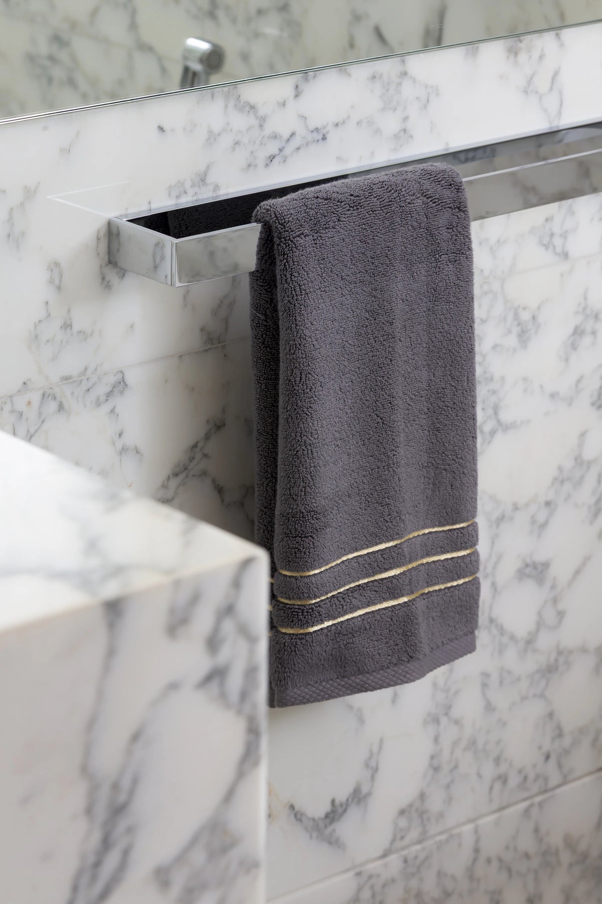 Grey Chateau Turkish cotton hand towel, on a chrome towel bar against marble 