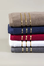 Stack of five Chateau Turkish cotton hand towels in brown, navy blue, maroon, white and grey with three gold border lines 