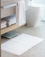 Retreat 1000 GSM white cotton bath mat on a herringbone bathroom floor
