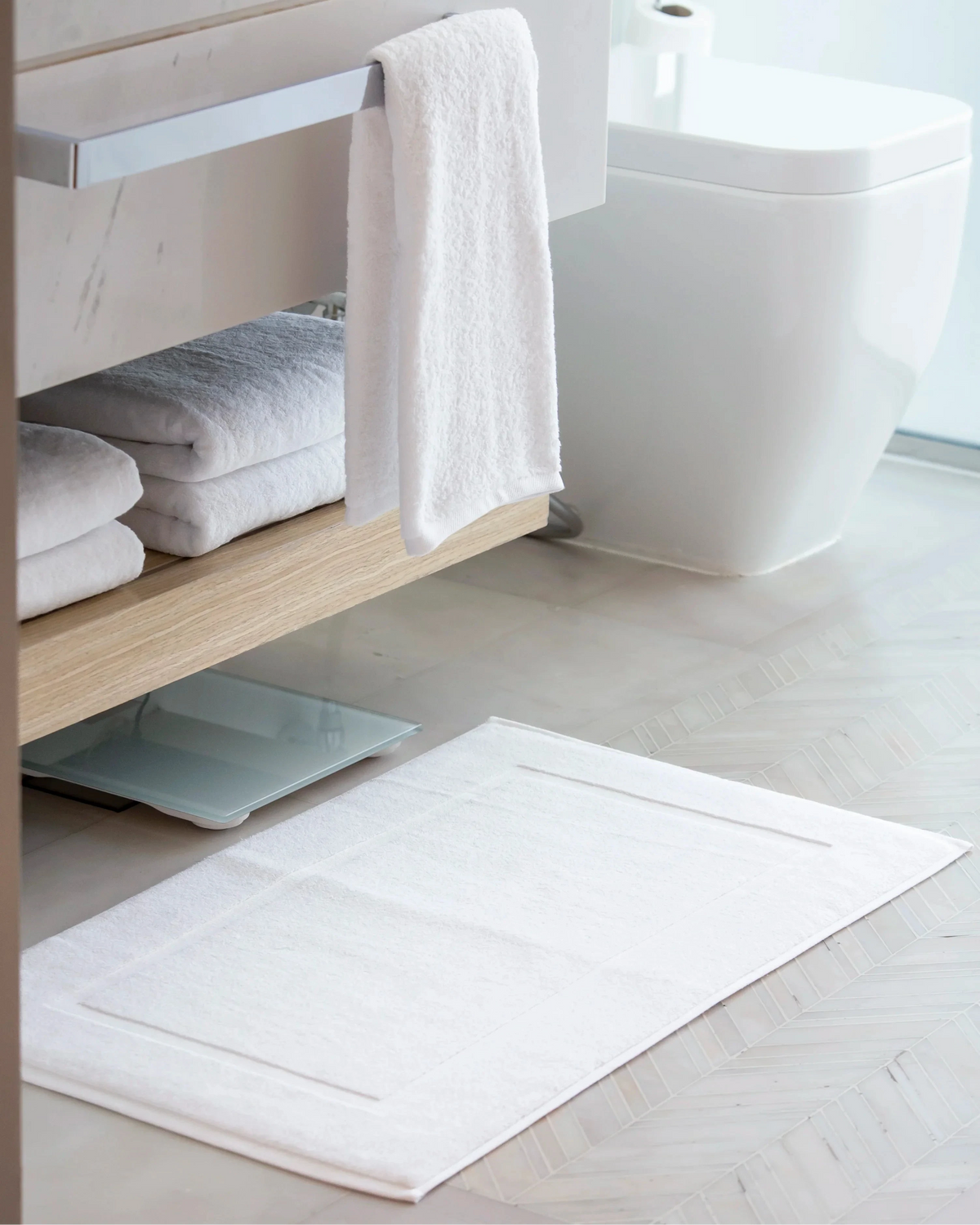 Retreat 1000 GSM white cotton bath mat on a herringbone bathroom floor