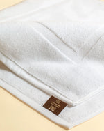 Close-up of the woven frame border on a Retreat white cotton bath mat