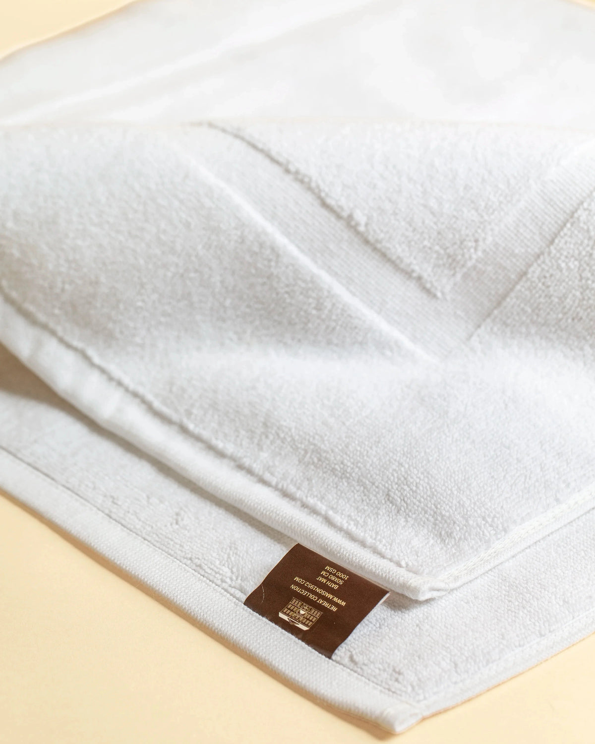 Close-up of the woven frame border on a Retreat white cotton bath mat