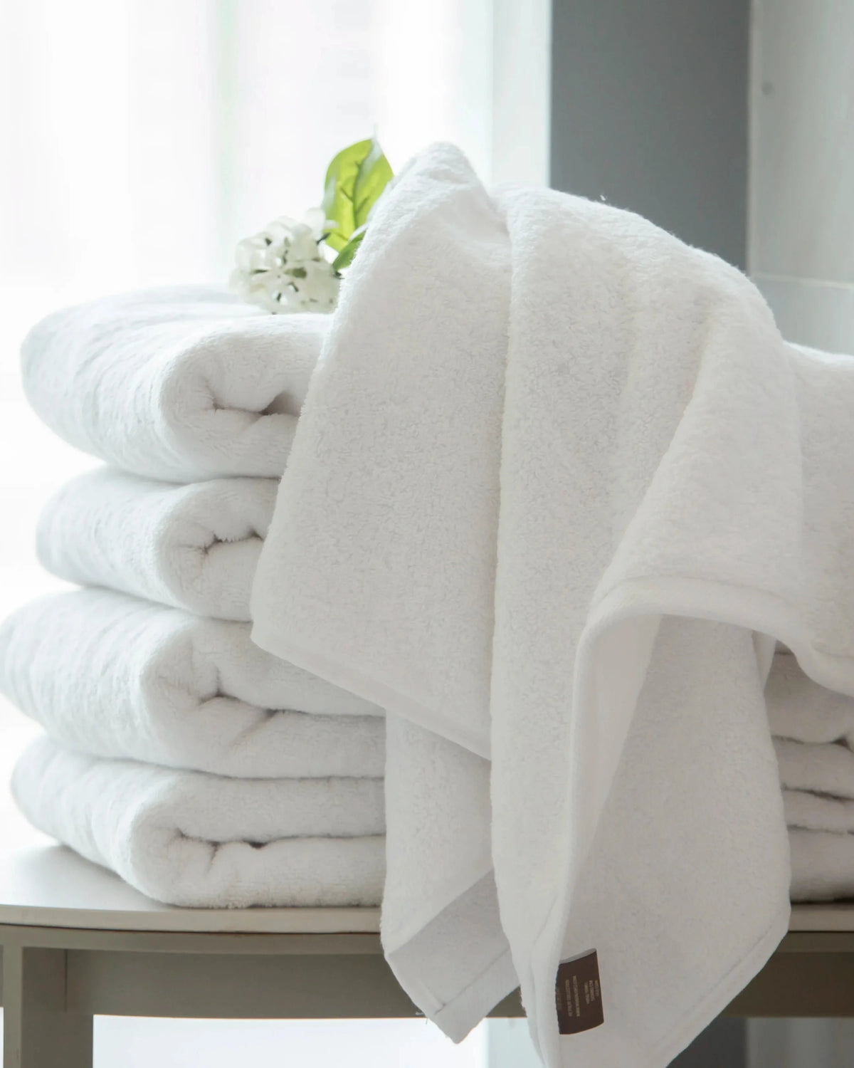 Retreat 650 GSM cotton bath towels folded and draped on a console table in a bright bathroom