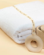Retreat white cotton bath towel folded and tied with a Maison 1952 gift ribbon