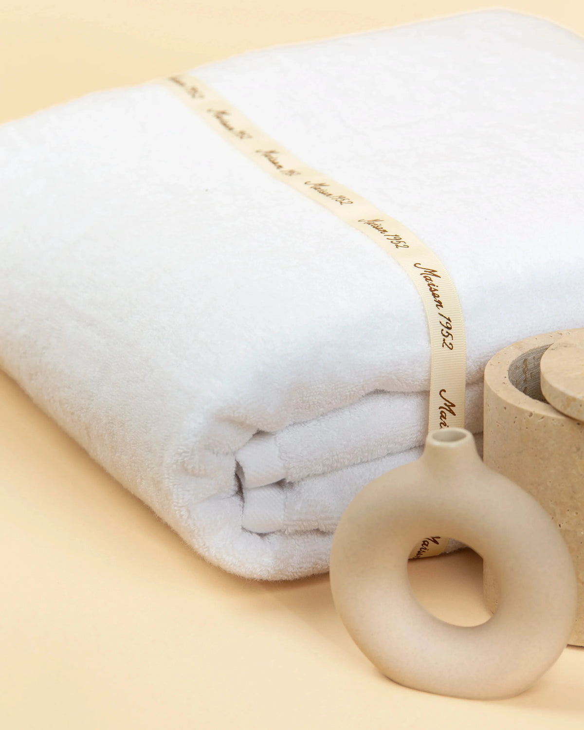 Retreat white cotton bath towel folded and tied with a Maison 1952 gift ribbon