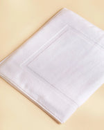 Retreat white cotton bath mat folded flat, showing the woven frame border