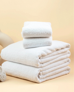 Retreat Essentials Set laid out: white cotton bath towel, hand towels and 1000 GSM bath mat