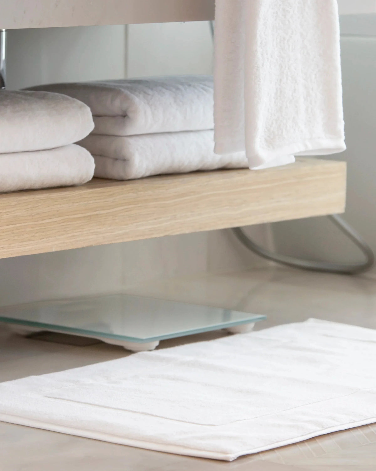 Retreat Essentials Set white towels on a vanity shelf with the bath mat on the floor