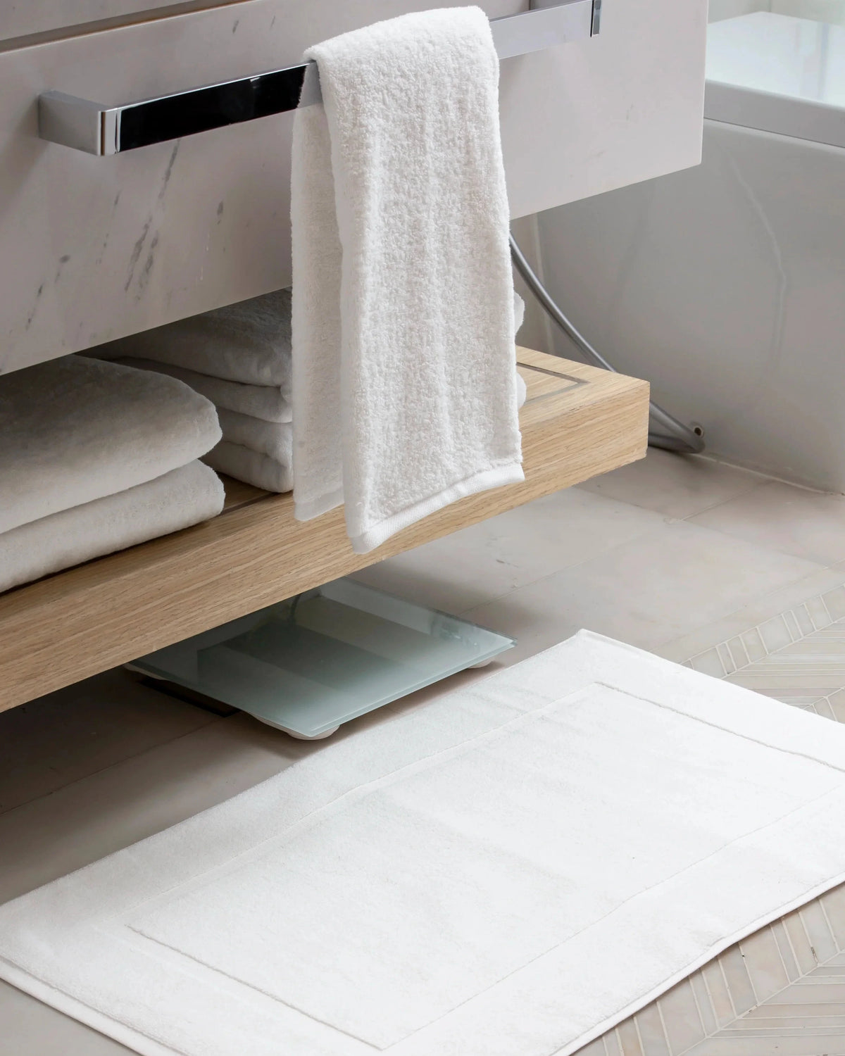 Retreat Essentials Set white cotton towels and bath mat in a marble bathroom