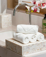 Retreat white cotton face towels rolled and stacked on a marble bathroom vanity