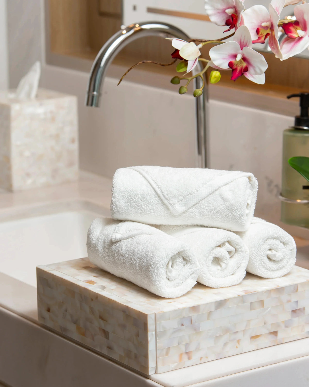 Retreat white cotton face towels rolled and stacked on a marble bathroom vanity